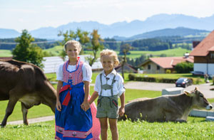 Kinder in Tracht vor einem Bauernhof